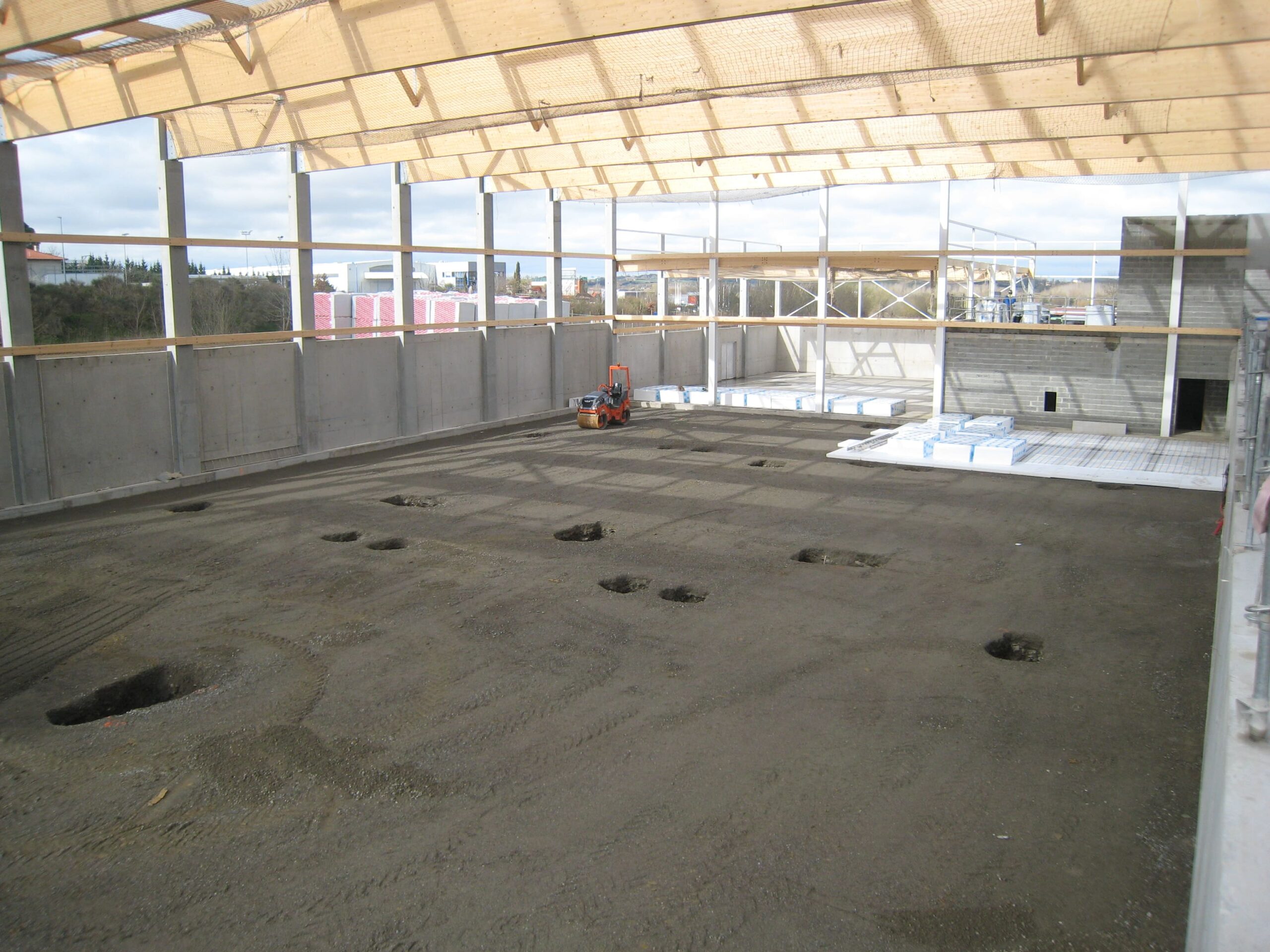 Chantier de bâtiment industriel en construction par opusbati à Toulouse, charpente bois métal et murs béton bruts