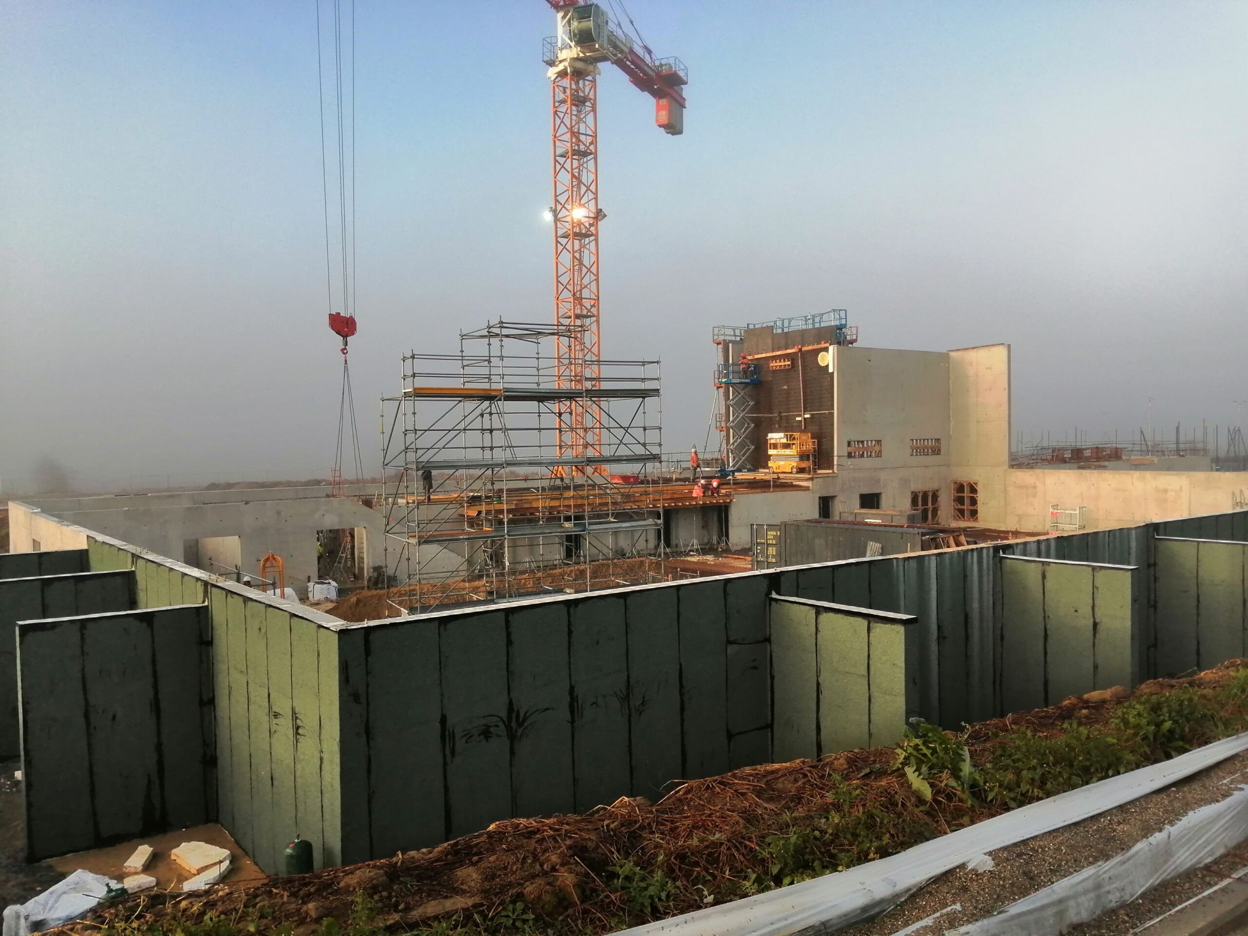 Chantier opusbati à Toulouse avec grue orange, échafaudage et murs en béton en cours de construction