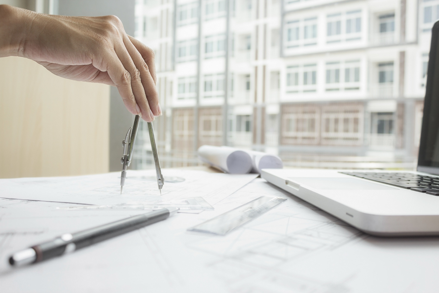 Architecte opusbati à Toulouse traçant des plans techniques au compas sur un bureau lumineux