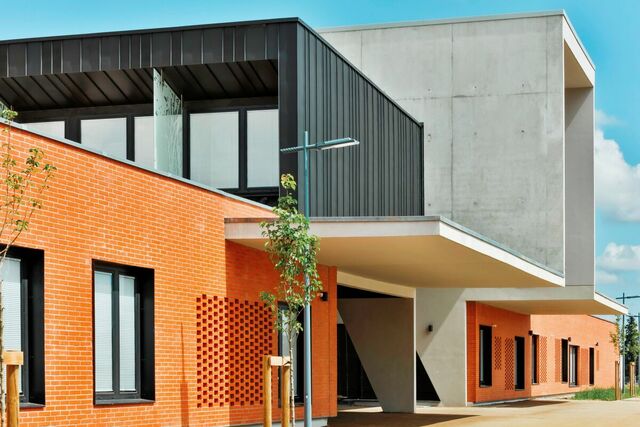 Bâtiment moderne en briques et béton réalisé par opusbati à Toulouse sous un ciel bleu