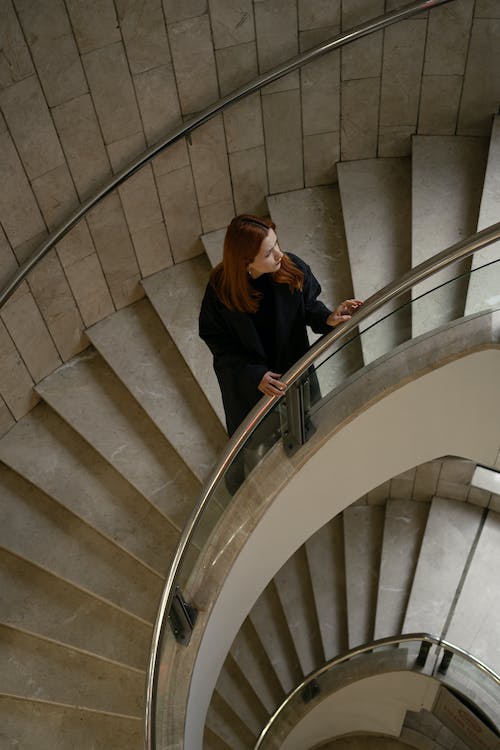 Femme sur escalier en colimaçon moderne en pierre et métal chez opusbati à Toulouse