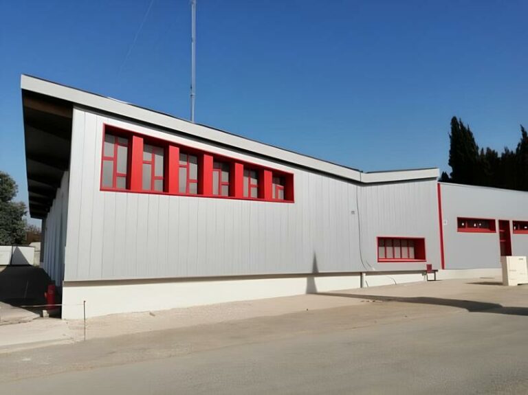 Bâtiment industriel moderne opusbati à Toulouse avec façade métallique grise et encadrements de fenêtres rouges