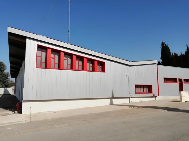 Bâtiment industriel moderne opusbati à Toulouse avec façade métallique grise et encadrements de fenêtres rouges