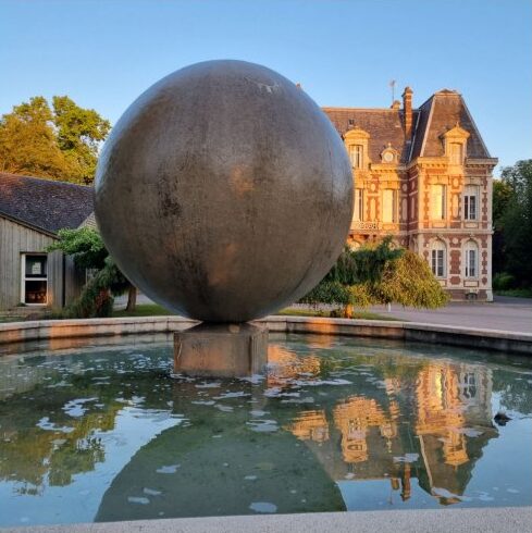 Sphère métallique sur bassin devant bâtiment classique au coucher du soleil, réalisation opusbati à Toulouse